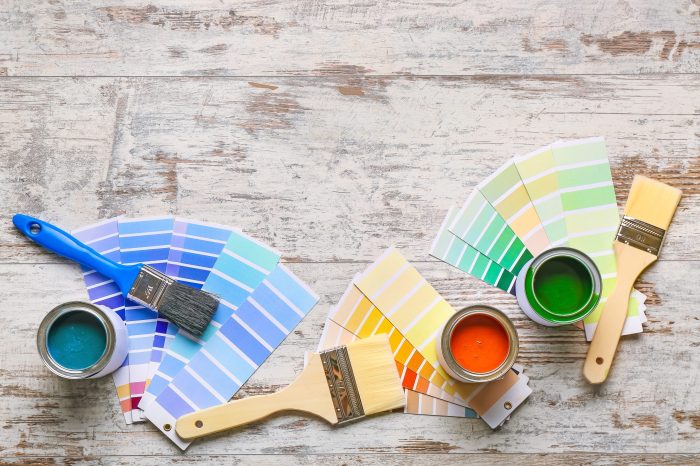 Color swatches with paints and brushes on wooden table